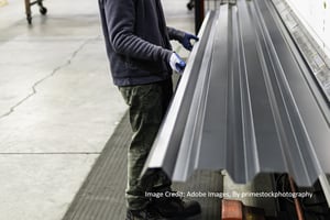 a man holds the edge of a Galvalume Metal Roofing panel 