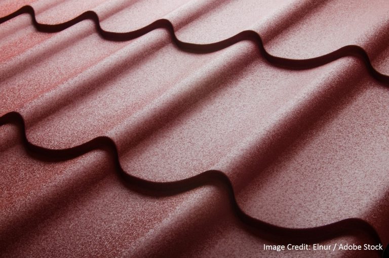 An extreme close-up macro shot of wavy reddish-pink roofing tiles reveals fine grain texture and rolling curves.