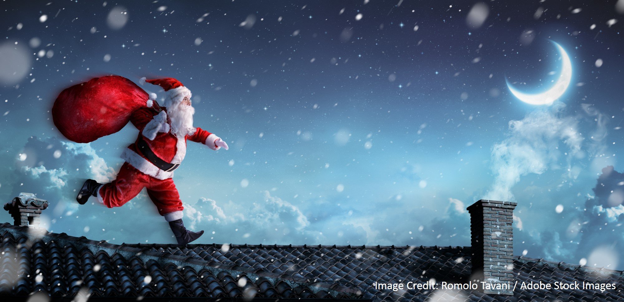 Santa Claus runs across a snow-covered tile roof carrying a red gift sack beneath a glowing crescent moon.