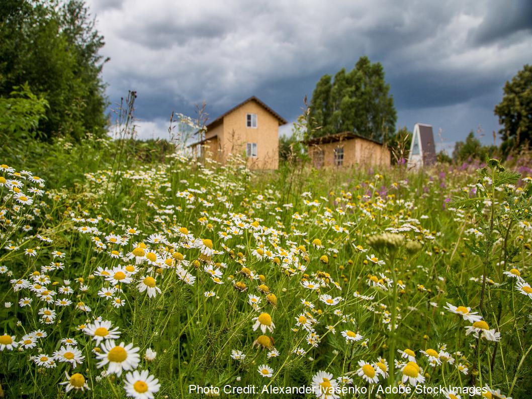 A rustic yellow home stands against a stormy sky, representing a residential setting for durable metal roofing in Round Rock.