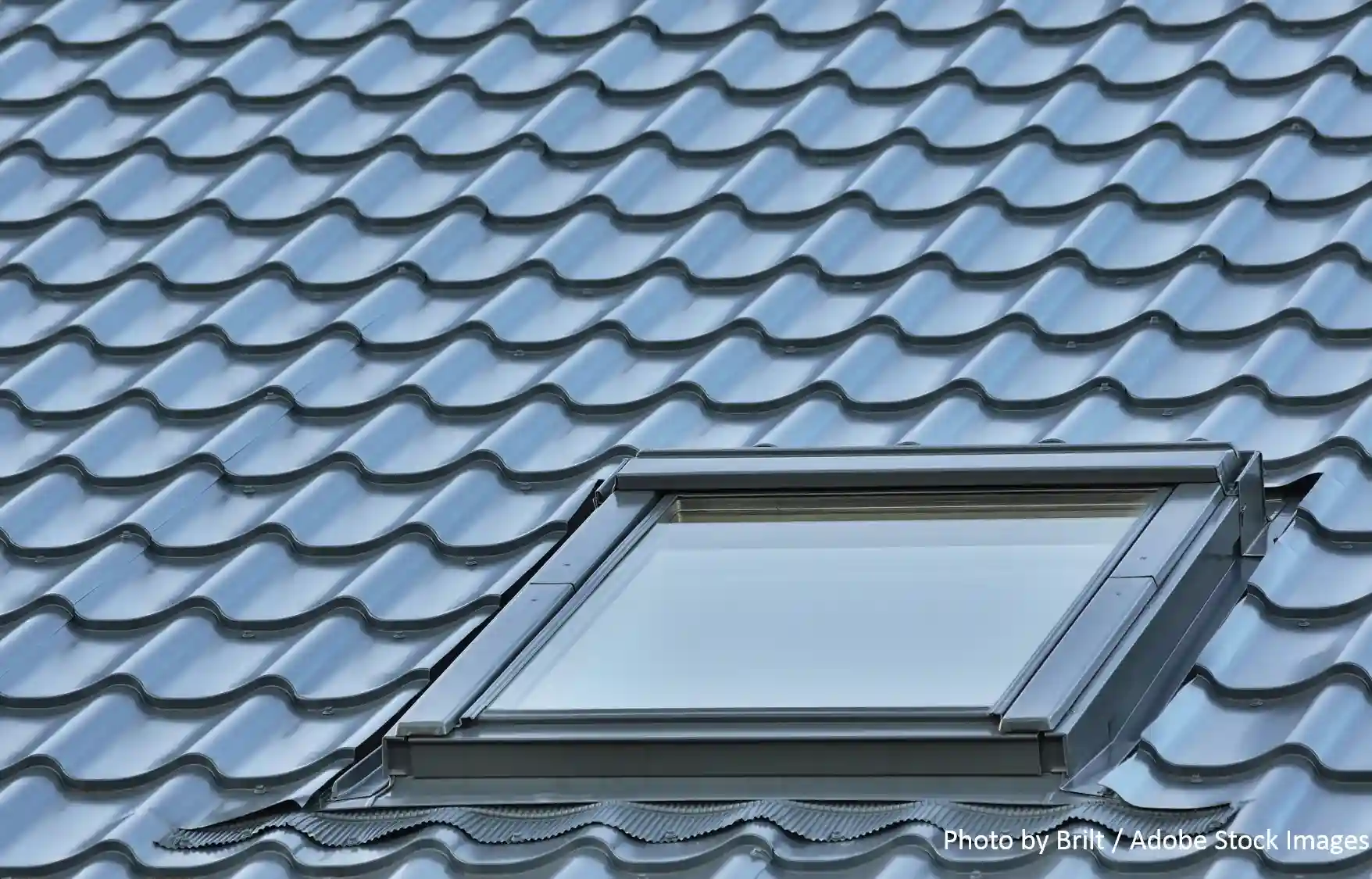 A textured metal roof with a skylight window, showcasing the energy-efficient metal roofing systems Longhorn Roofing installs.