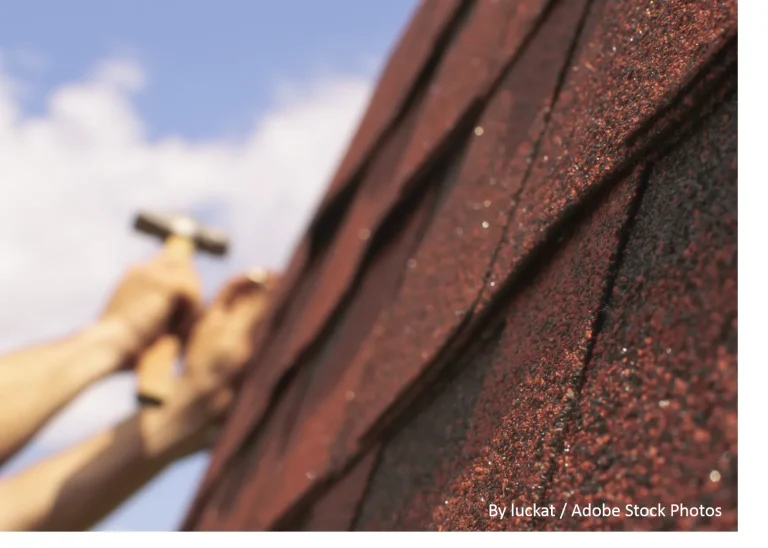 A worker's hands hammer dimensional shingles into place, part of a professional composite roof installation by Longhorn Roofing.