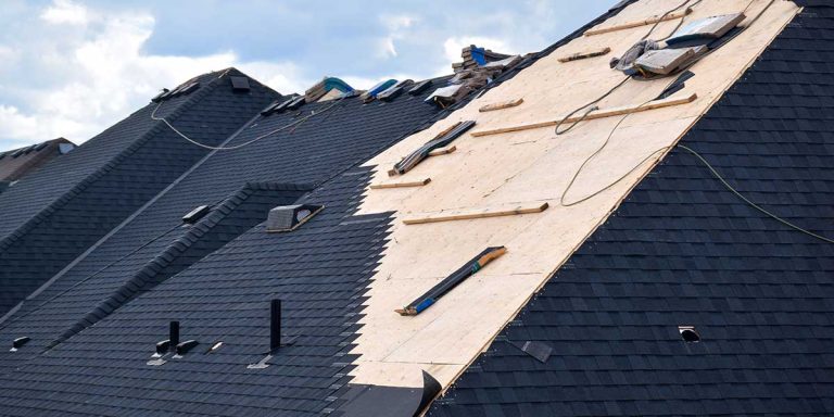 Exposed plywood roof decking during a full shingle replacement, showing how often old wooden roof sheathing needs total replacement.