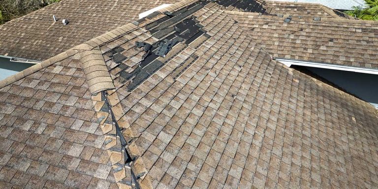 Aerial view of a damaged shingle roof with missing, torn asphalt shingles and exposed underlayment causing structural sagging issues.