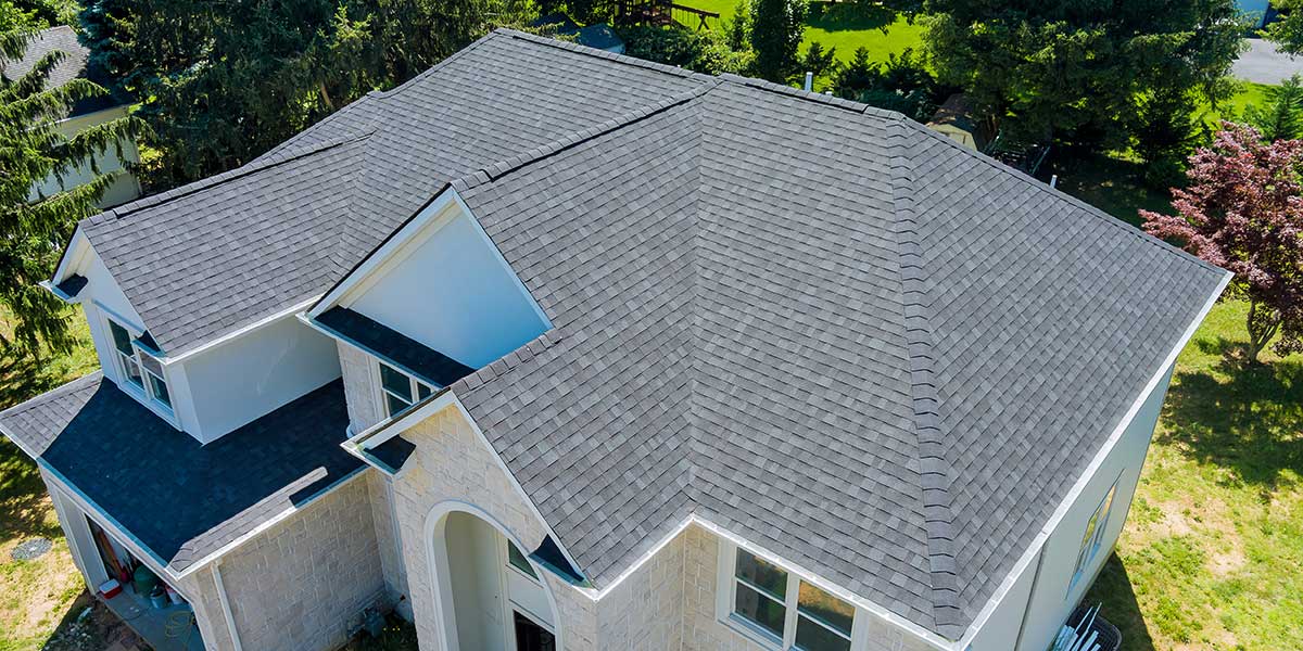 Aerial top view of a modern house featuring a newly installed dark gray shingle roof for residential permitting reference.