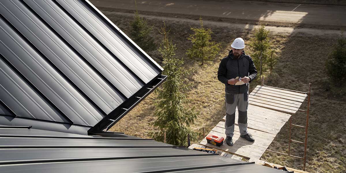 Roofing contractor inspecting a standing seam metal roof to ensure compliance with HOA roofing requirements in Austin, Texas.